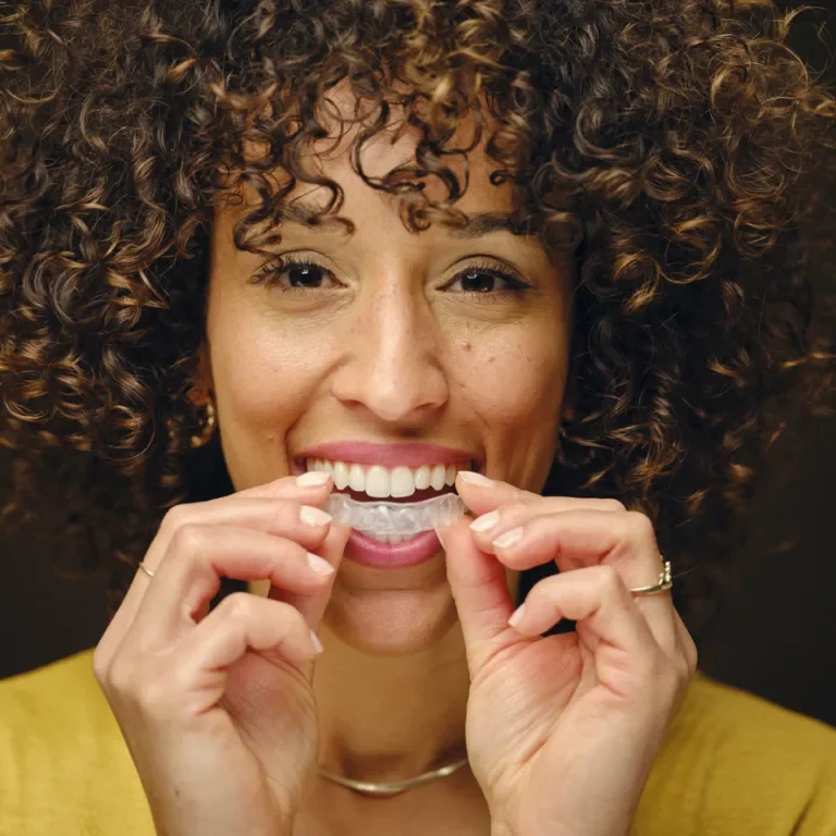 Happy Young Woman Holding Inivisible Teeth Aligners A happy young woman holding invisible clear teeth aligners.